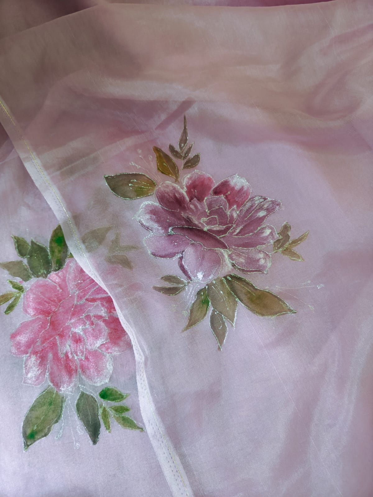 Close view of a hand-painted rose motif on blush organza